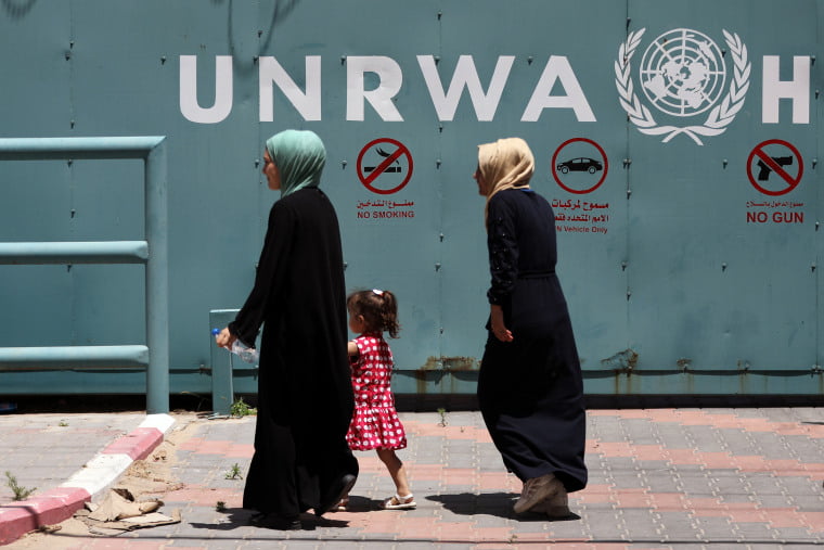 Palestinian women walk in front of the headquarters of the