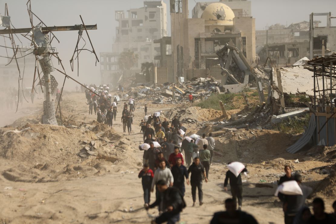 Palestinians, who are unable to meet their basic needs due to the Israeli army's obstruction of humanitarian aid, receive a bag of flour from an aid truck that arrived at al-Rashid Street in the west of Gaza City, Gaza.