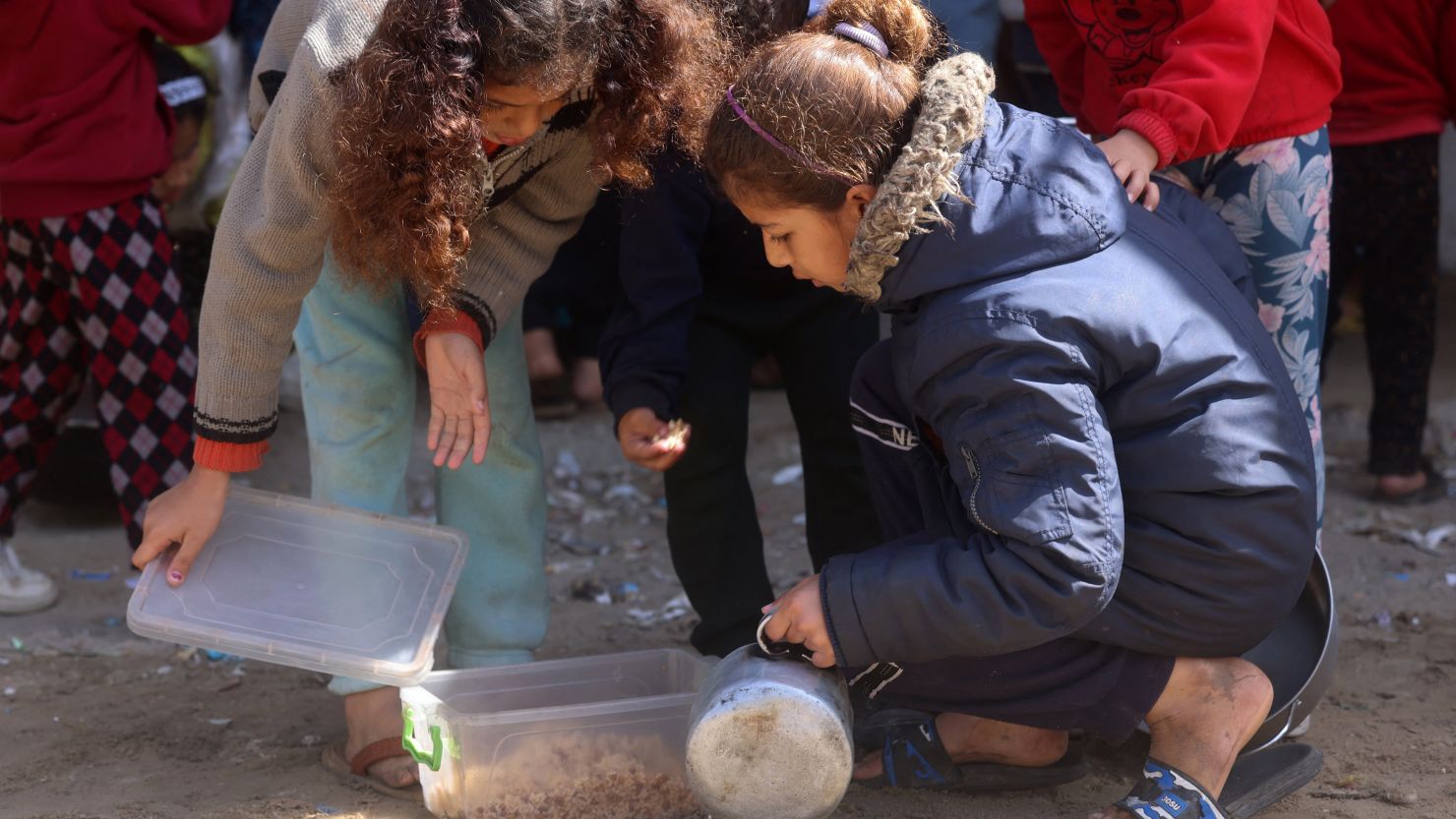 Displaced Palestinian children prepare to have a meal of rice near a food distribution point in Rafah in the southern Gaza Strip, amid the ongoing conflict between Israel and Hamas militants.