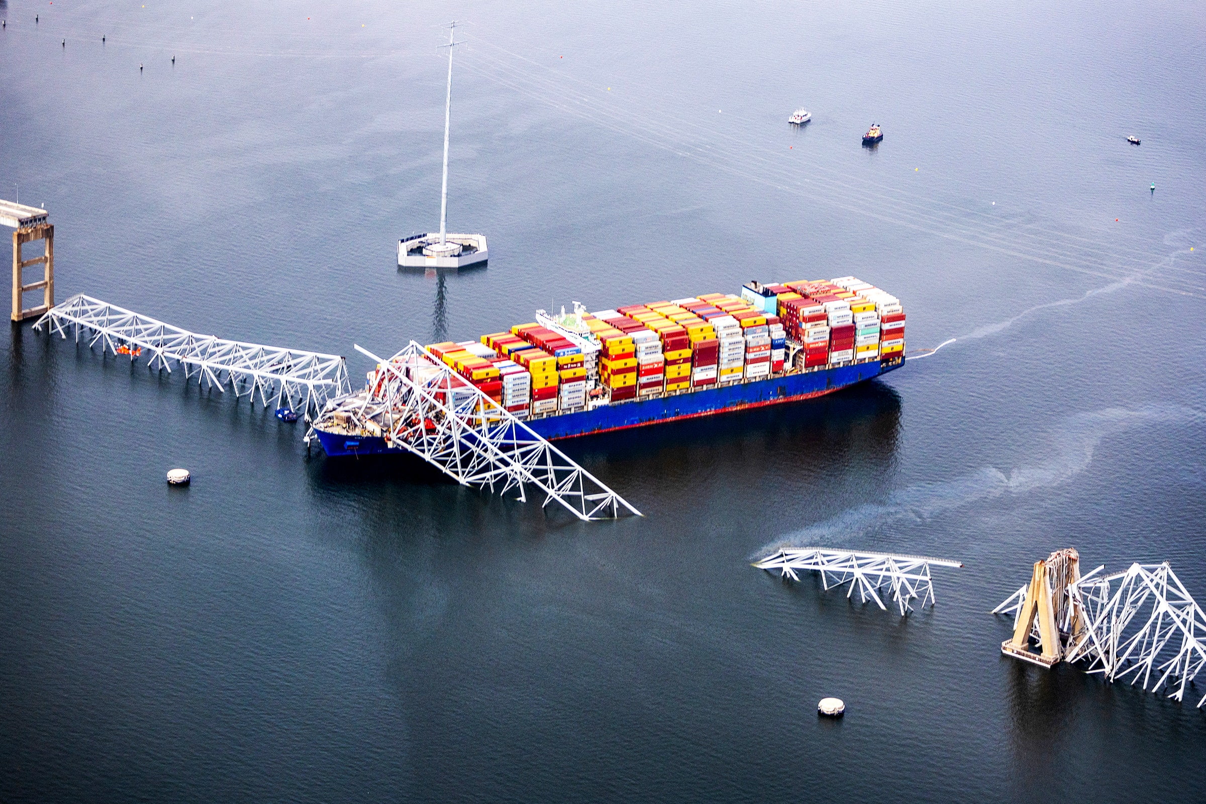 Aerial view of a large cargo ship under a collapse bridge over a wide river