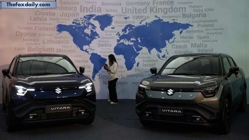 A visitor uses her phone next to Maruti Suzuki's e-Vitara SUV at the firm's Gujarat plant in Hansalpur Becharaji