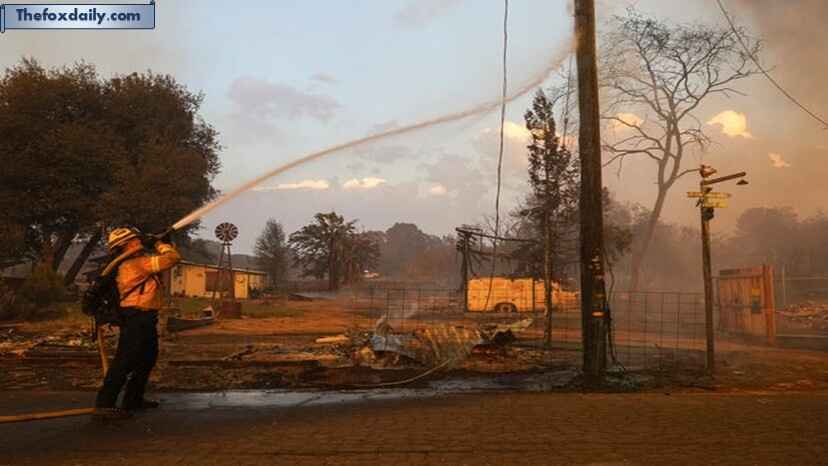 A firefighter hoses down a burning utility pole as flames engulf Chinese Camp Town as wildfires rage in Tuolumne County