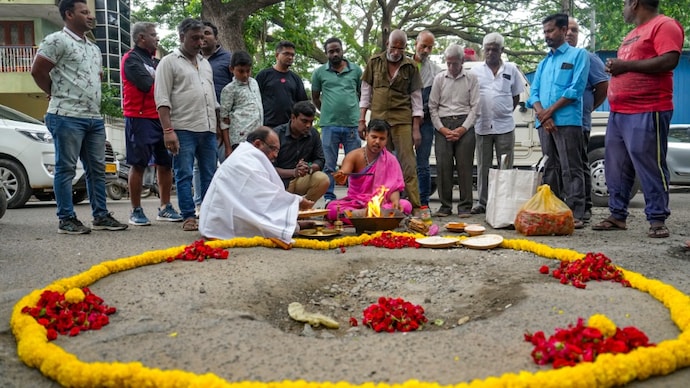 Bharatinagar Residents Association members performed puja of a pothole encircled with flowers over the deteriorated road condition in Bengaluru. (PTI Image)
