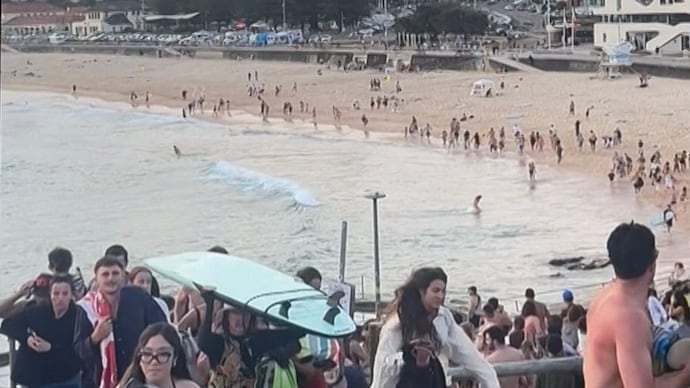 Image shows beach-goers fleeing Bondi Beach after gunmen opened fire, in Sydney.
