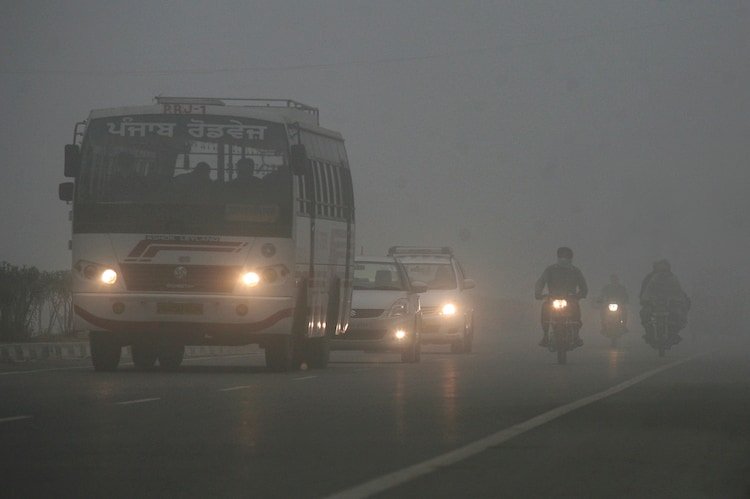 Vehicles travel at a highway amid dense fog on a winter morning in Punjab.