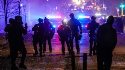 Federal agents stand guard after deploying tear gas in Minneapolis.