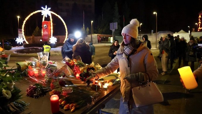 A woman leaves flowers outside the "Le Constellation" bar, after a fire and explosion during a New Year's Eve party where several people died.