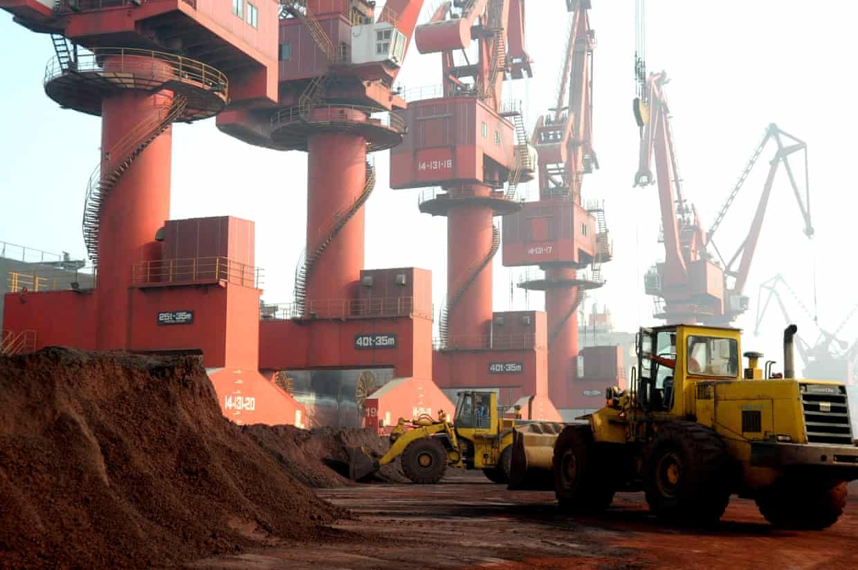 Workers transport soil containing rare earth elements for export at a port