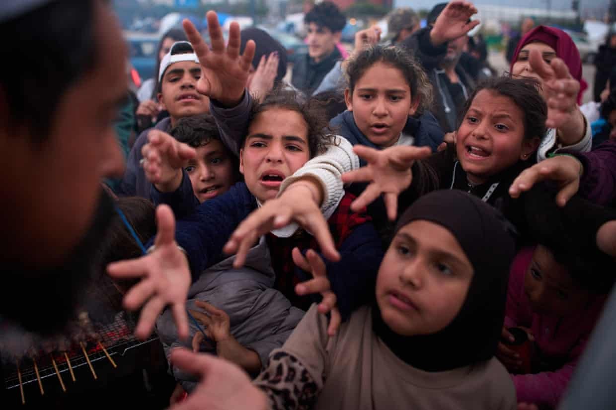 Children crowd together to reach for donated food in Beirut
