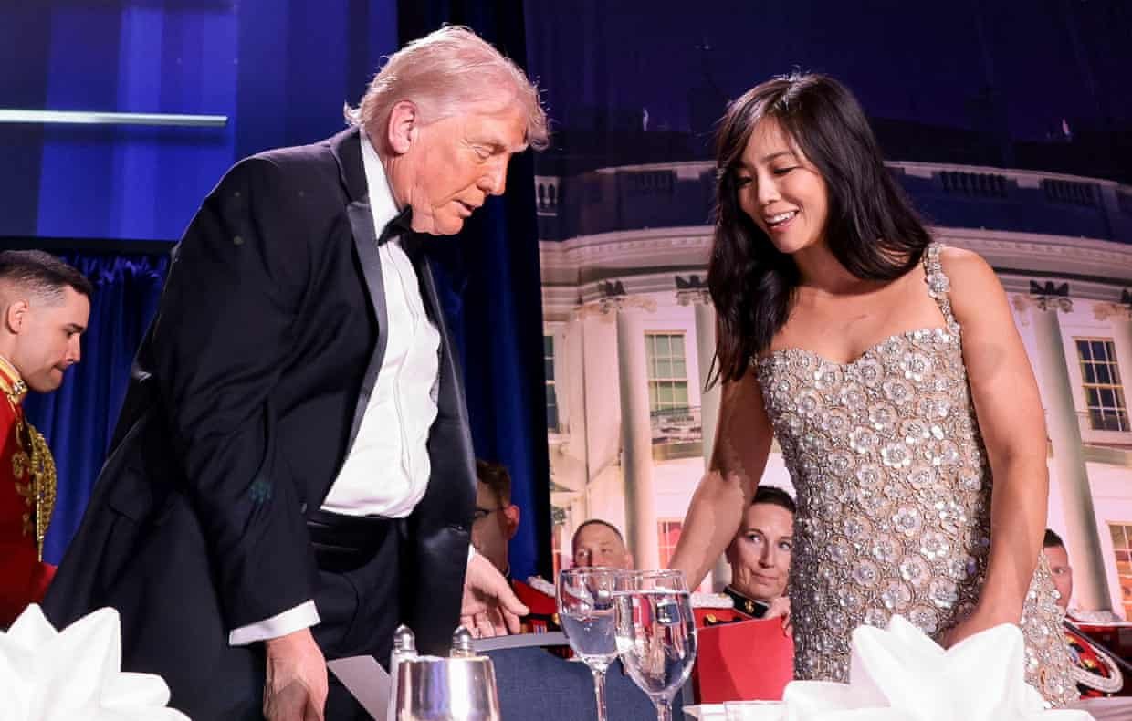 Donald Trump and Weijia Jiang taking their seats at a table in the room where the dinner was taking place