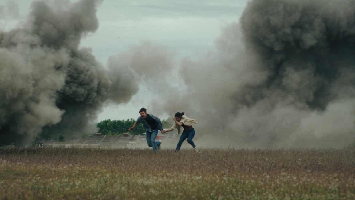 Couple running between plumes of smoke in a field.