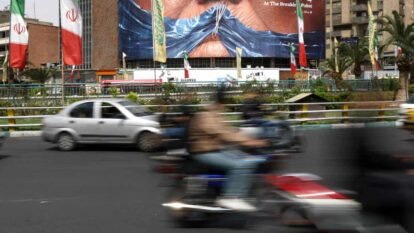 People drive past anti-US billboard depicting Donald Trump and the Strait of Hormuz in Tehran.