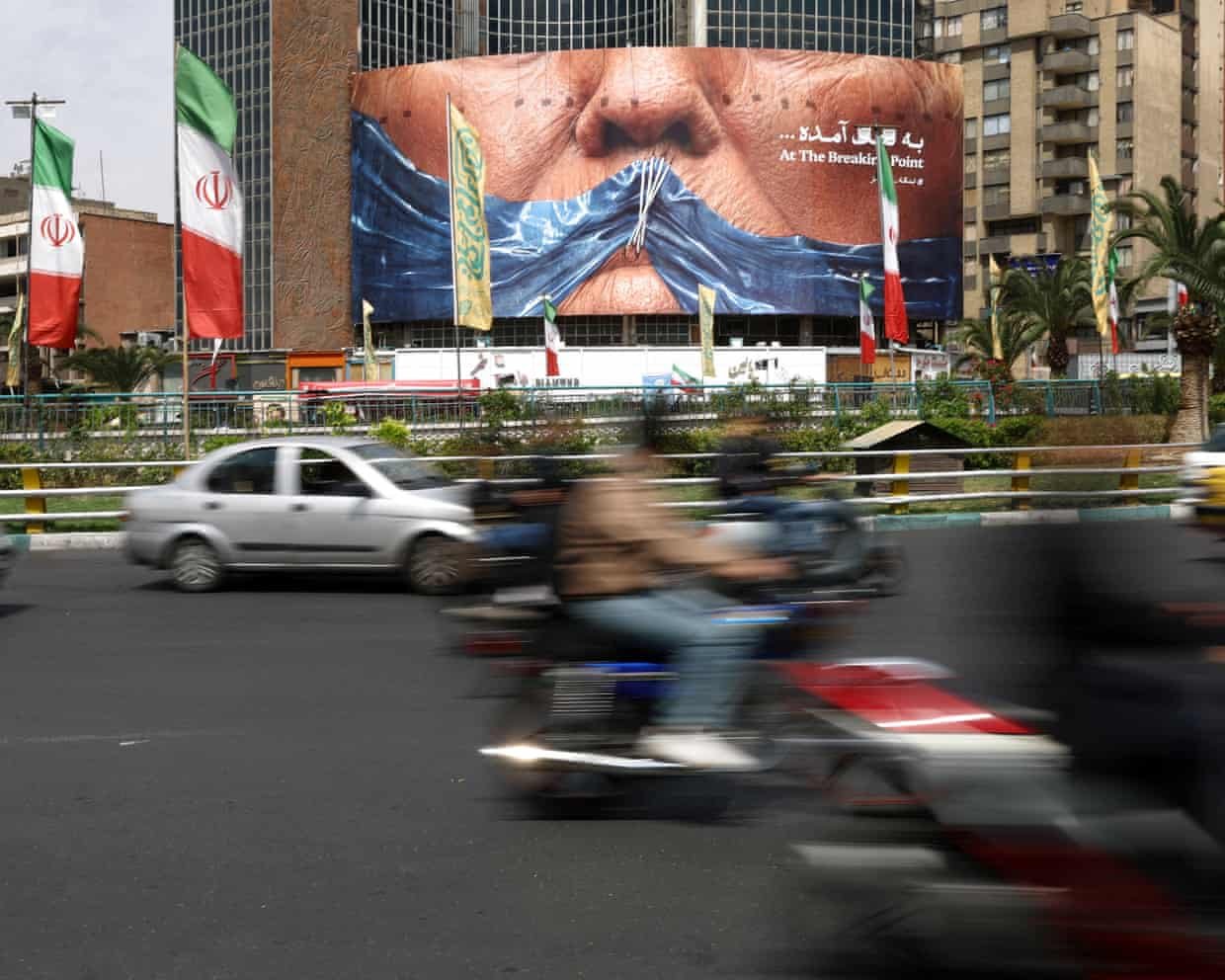 People drive past anti-US billboard depicting Donald Trump and the Strait of Hormuz in Tehran.