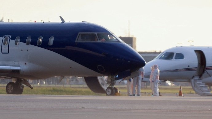 Health workers in hazmat suits stand next to an air ambulance on the day hantavirus patients arrive at Schiphol Airport near Amsterdam, Netherlands.