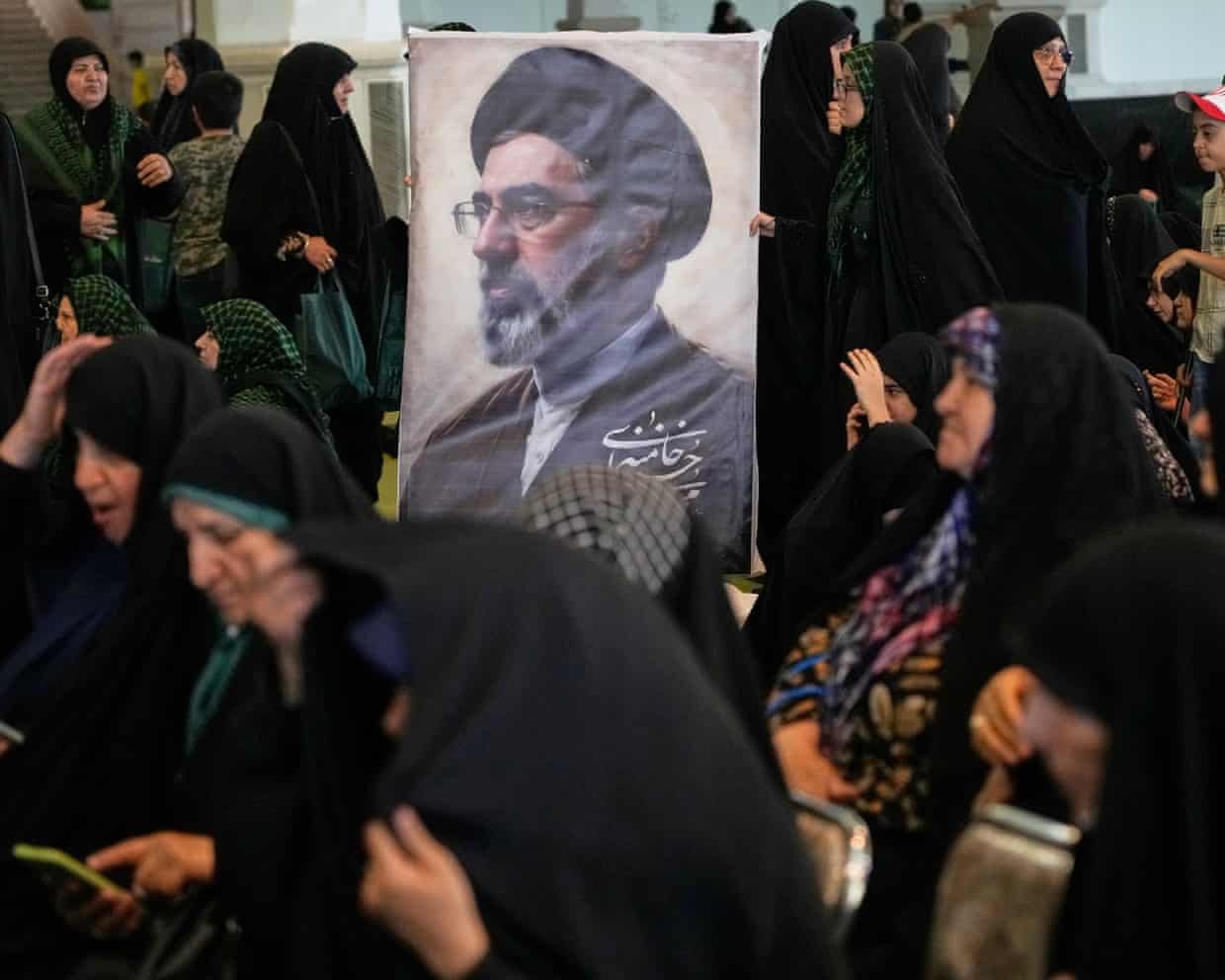 Women gather around a portrait of Iran's Supreme Leader, Ayatollah Mojtaba Khamenei, during a ceremony honoring the armed forces