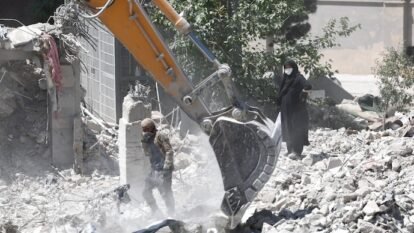 A woman stands amid the rubble of her home, damaged in a US strike in Iran.
