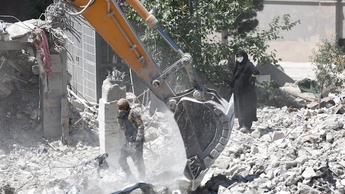 A woman stands amid the rubble of her home, damaged in a US strike in Iran.
