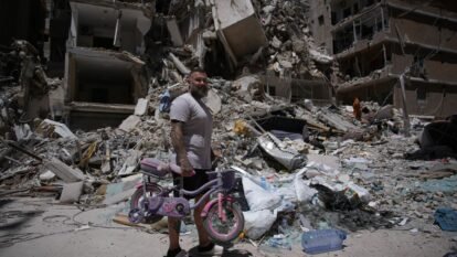 War: Barber Wissam Srour, 41, holds his daughter's bicycle recovered from his barbershop as he searches for belongings in the rubble of the shop, damaged in an Israeli strike, in the southern port city of Tyre, Lebanon.