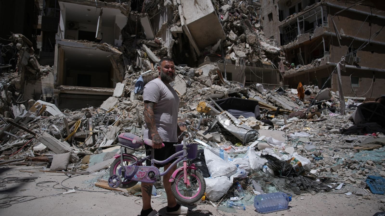 War: Barber Wissam Srour, 41, holds his daughter's bicycle recovered from his barbershop as he searches for belongings in the rubble of the shop, damaged in an Israeli strike, in the southern port city of Tyre, Lebanon.
