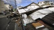 Person on a bike passes by collapsed houses, a day after an earthquake in Yatsushiro, Kumamoto prefecture