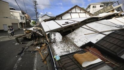 Person on a bike passes by collapsed houses, a day after an earthquake in Yatsushiro, Kumamoto prefecture