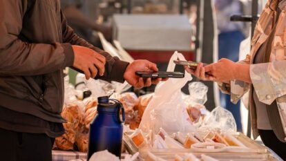 A shopper uses a smartphone to pay for produce during a farmers market at the Ferry Building in San Francisco on July 16, 2026.