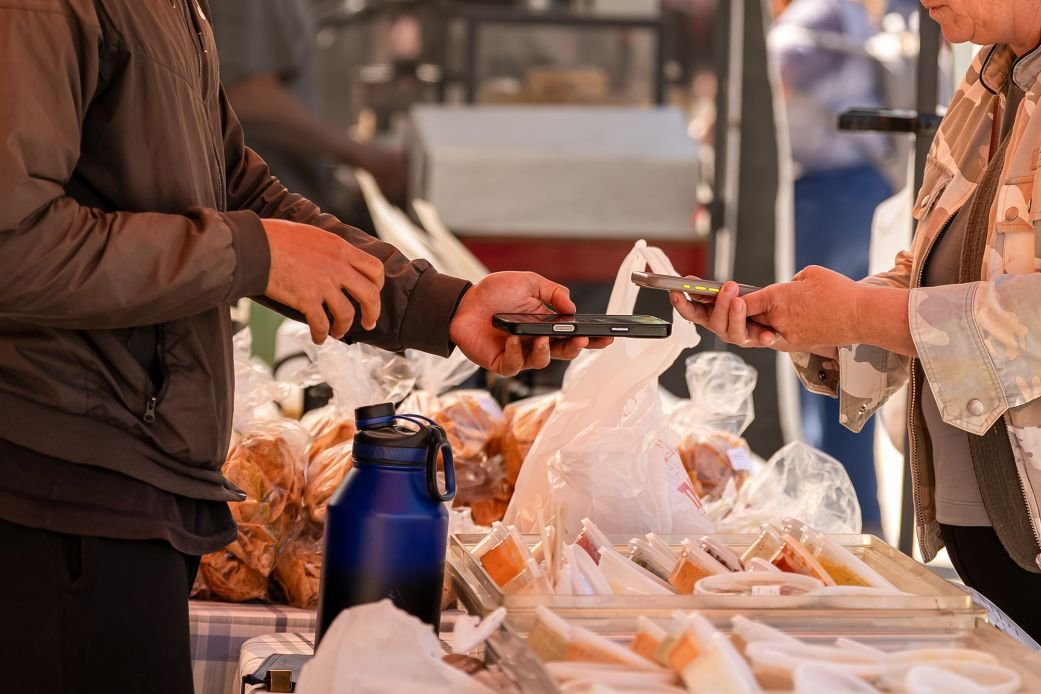 A shopper uses a smartphone to pay for produce during a farmers market at the Ferry Building in San Francisco on July 16, 2026.