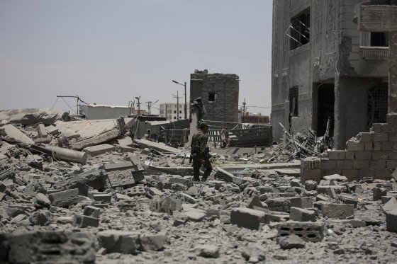A soldier inspects rubble in the street.
